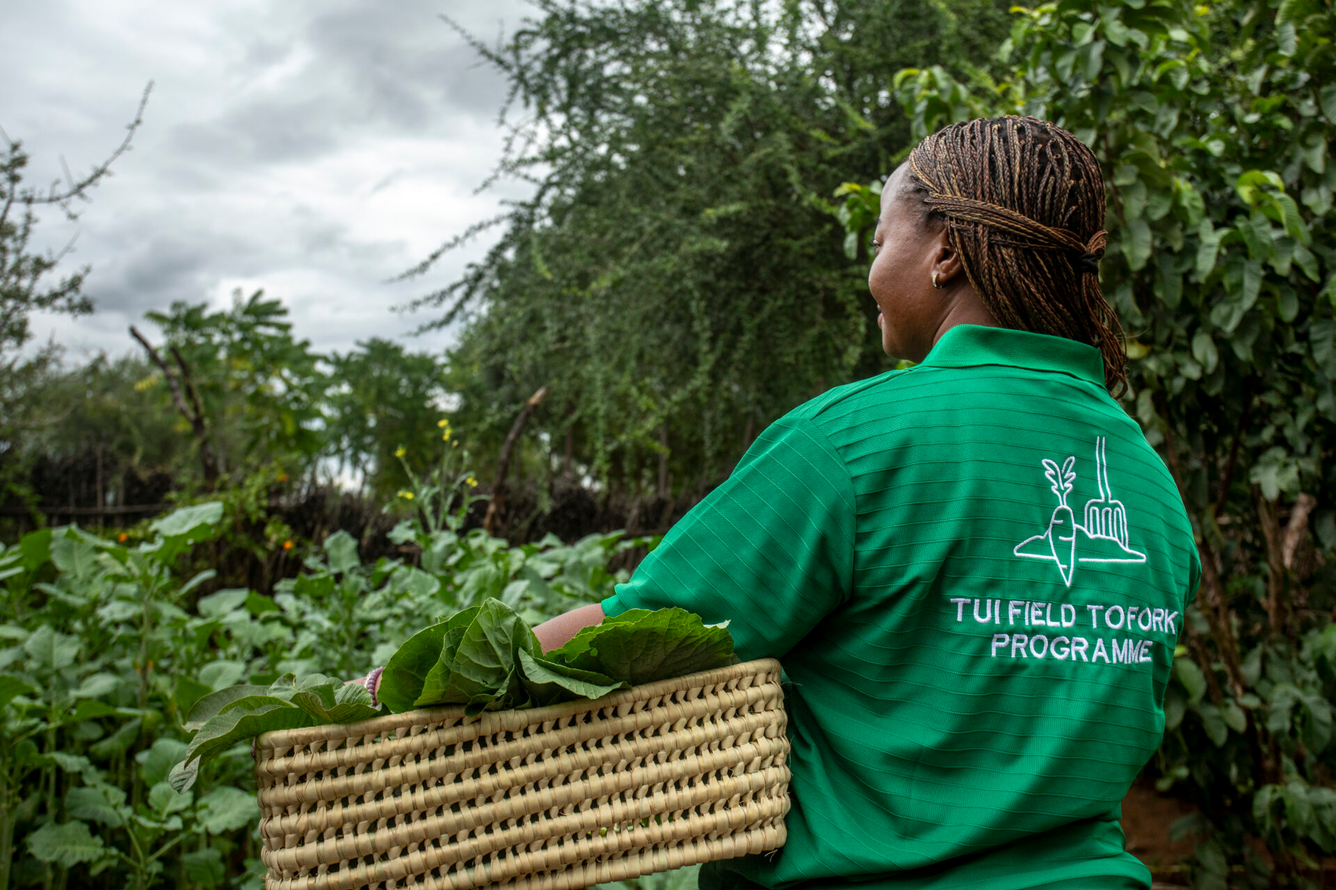 A women in a green t-shirt with the TUI Field to Fork branding holding a basket
